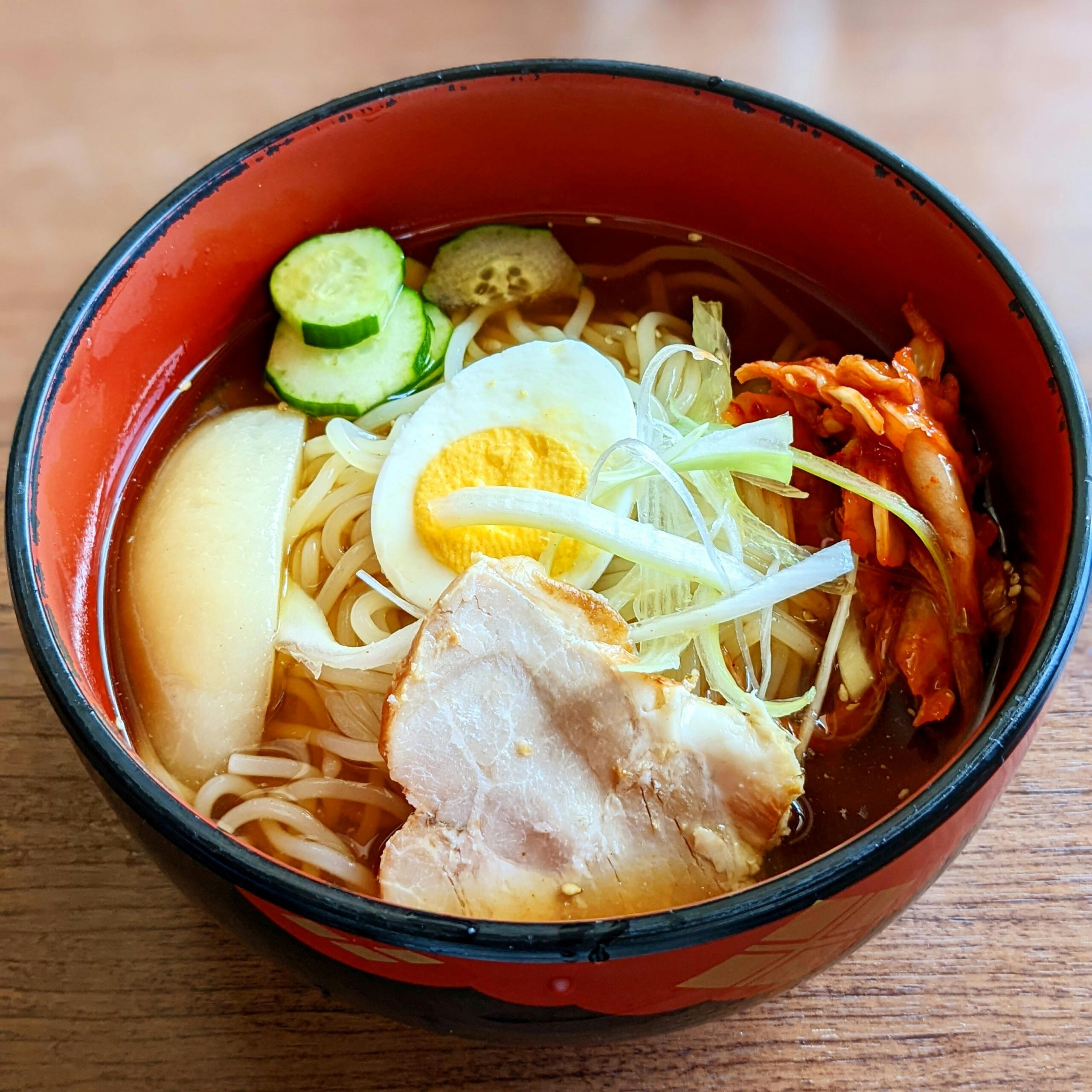 A vibrant bowl of ramen noodles with egg, pork, and fresh vegetables, perfect for food photography.