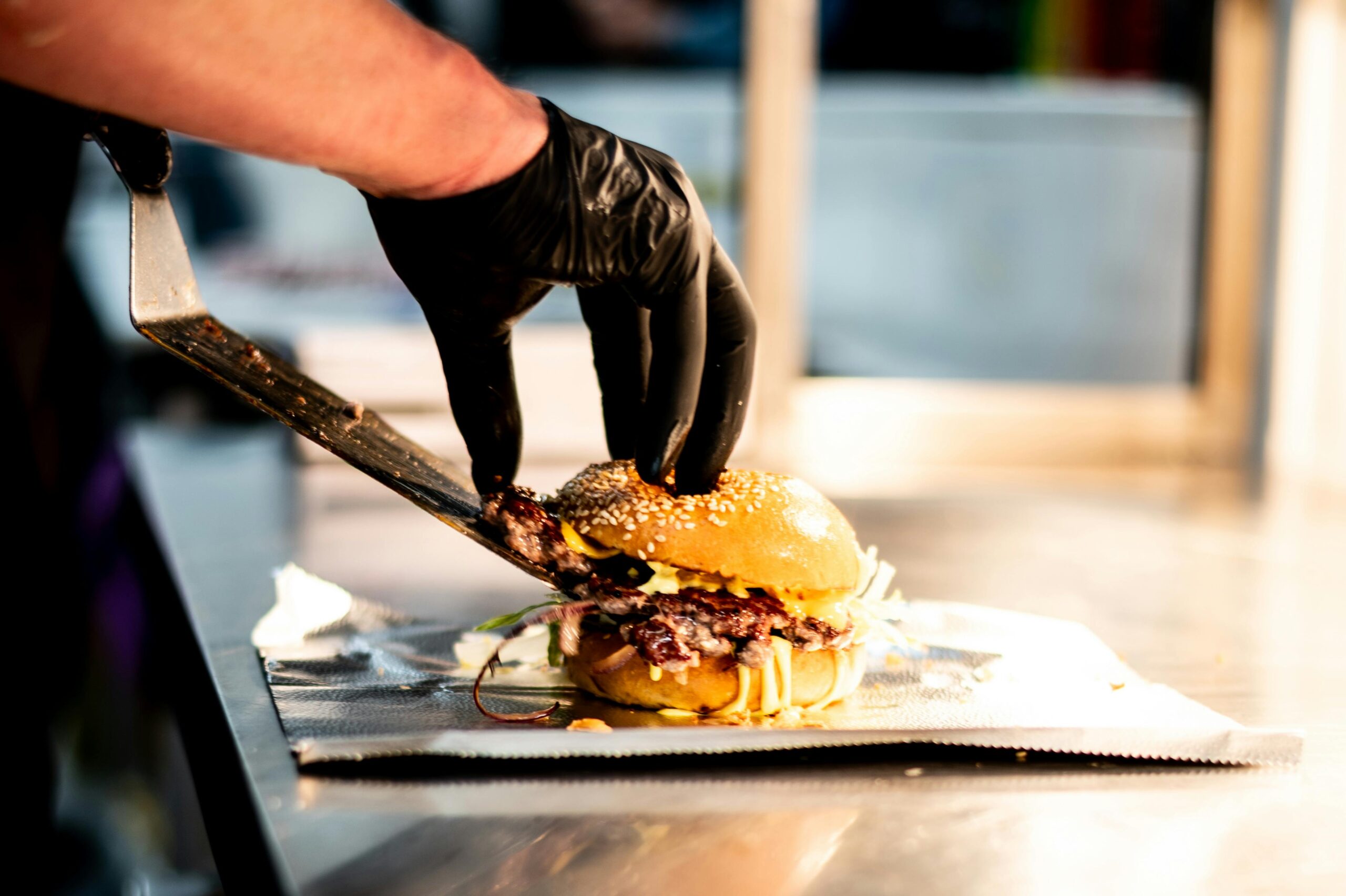 A chef skillfully prepares a gourmet burger with unique toppings in a professional kitchen setting.