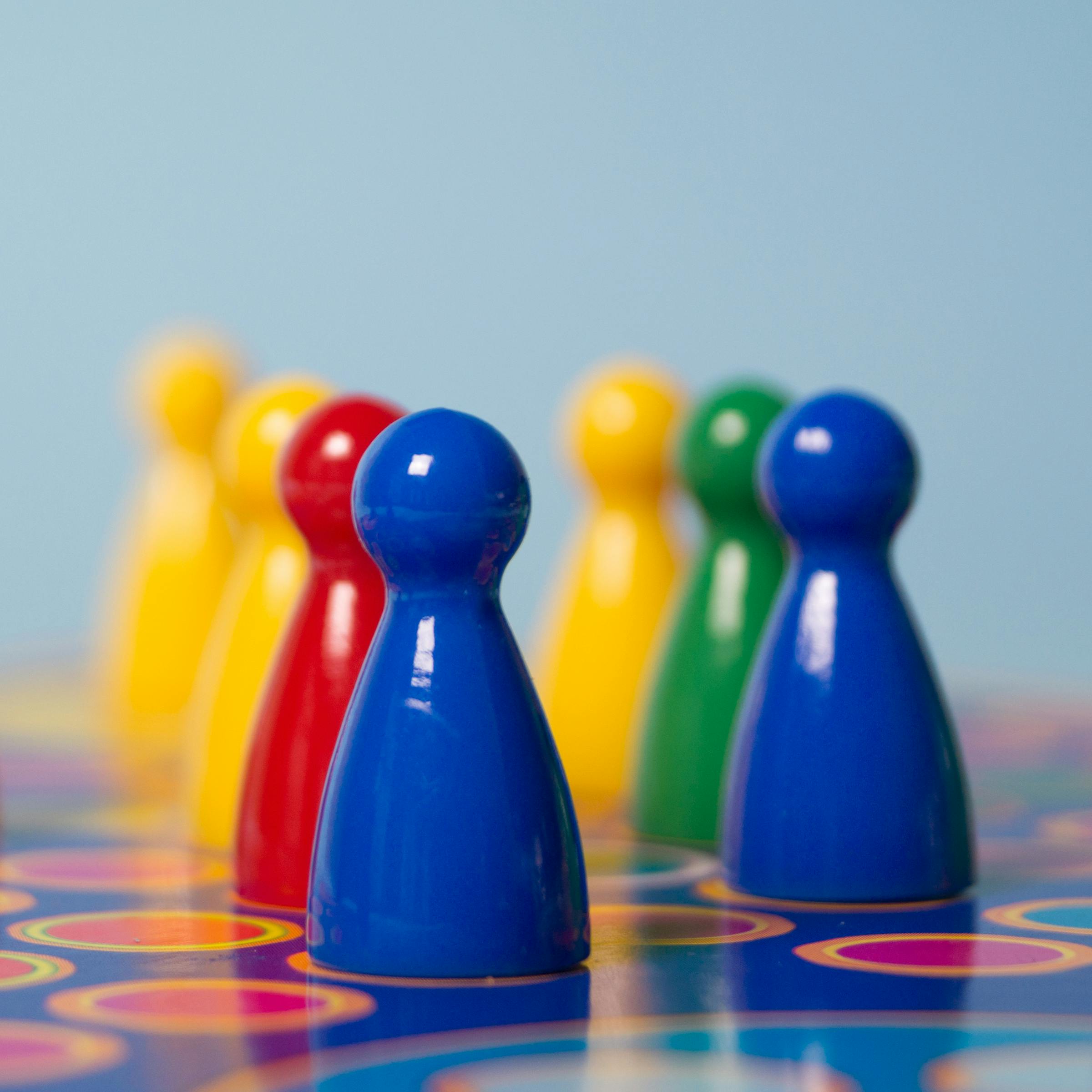 Vivid colored board game pawns arranged on a decorative game board surface.